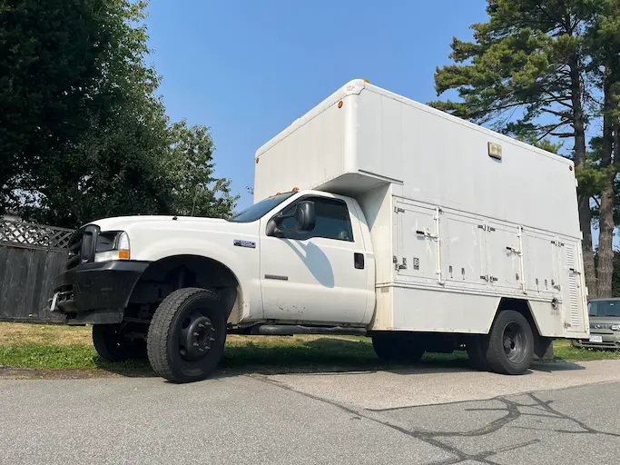 The Haul Away Junk Removal white box truck parked beside tall evergreens